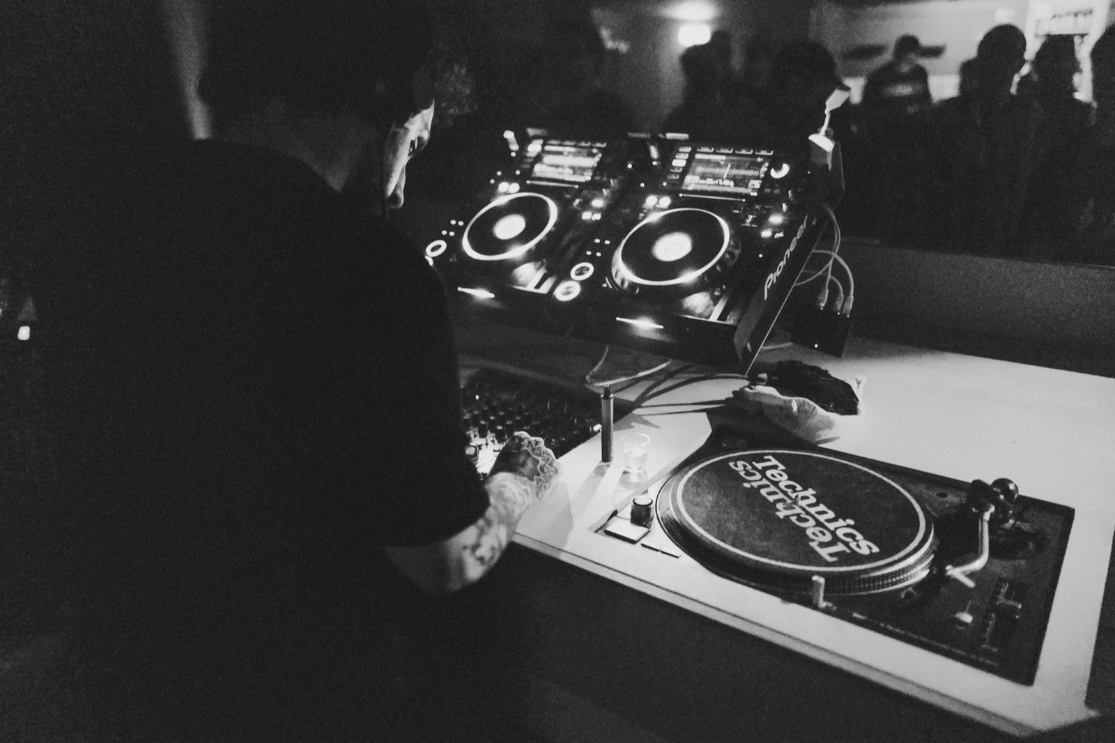 Atabak Taz am DJ-Pult — CDJs und Technics-Turntable im dunklen Club
